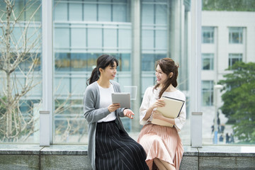 タブレットを片手に会話するOLたち