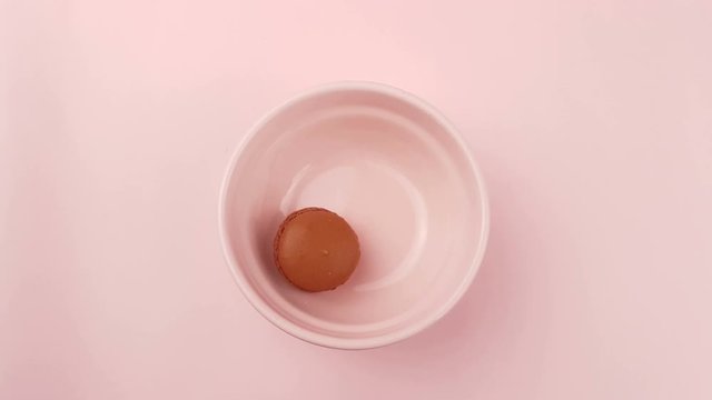 Sweet color macaroons or macaron in pink plate on pastel surface. Close up.