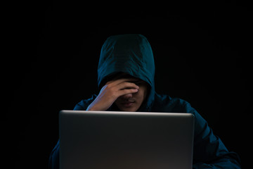 Hacker in a dark hoody sitting in front of a notebook. Computer privacy attack