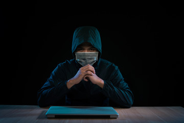 Asian hacker hacking computer network with laptop in dark. Cyber security concept
