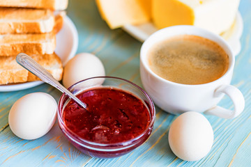 Breakfast with coffee, eggs, toasts, cheese, jam