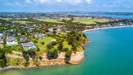 Naklejka premium Aerial view on residential suburb on the top of rocky cliff, facing sunny harbour. Auckland, New Zealand.