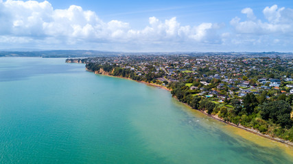 Aerial view on residential suburb on the top of rocky cliff, facing sunny harbour. Auckland, New Zealand.