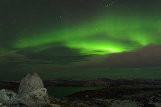 Northern Lights, polar lights over the hills and tundra in winter.Huge stone.