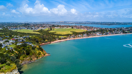 Obraz na płótnie Canvas Aerial view on a residential suburb surrounded by beautiful harbor at sunny day. Auckland, New Zealand.