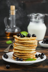 Stack of sweet pancakes with fresh berries and mint on white plate on wooden rustic table