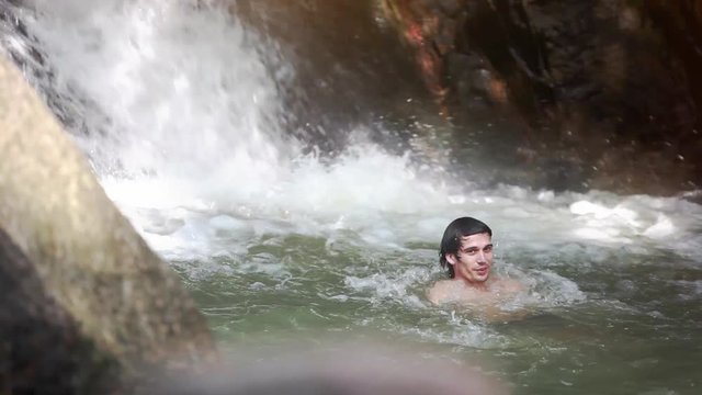 Happy handsome man relaxing under stream water in waterfall in tropical jungle. 1920x1080