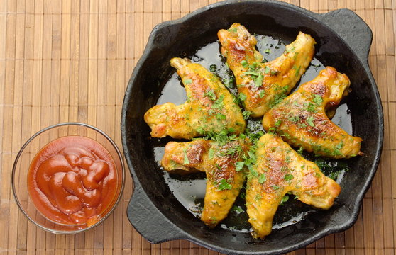 chicken winggs and tosts on a pan and ketchup
