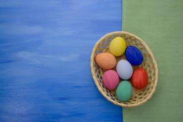 Easter eggs in yello basket on blue and green fabric backgrounds S1V3