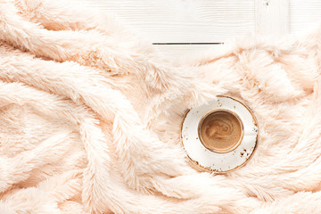 A cup of coffee on a wooden table and a warm blanket. Autumn or Winter concept, Flat lay