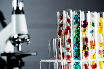 Laboratory Microscope, pills and test tubes. Scientific and healthcare research background.