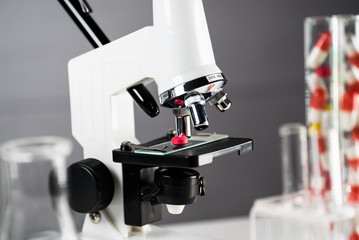 Laboratory Microscope, pills and test tubes. Scientific and healthcare research background.