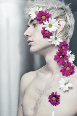 The aesthetic guy with flowers on his face looks away