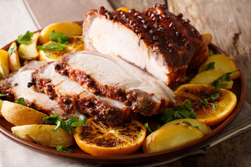Homemade Hot Pork Tenderloin with Spices with a garnish of potatoes, oranges and apples close-up. Horizontal
