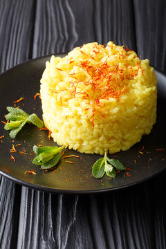 traditional risotto alla milanese with saffron is decorated with mint closeup on a plate. vertical