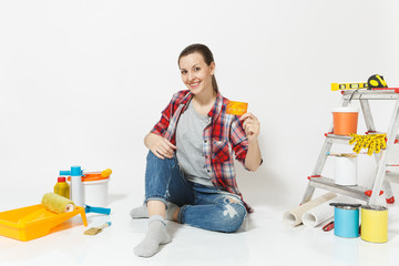 Cute woman holding credit card with money sitting on floor with instruments for renovation apartment isolated on white background. Wallpaper accessories for gluing painting tools. Repair home concept.