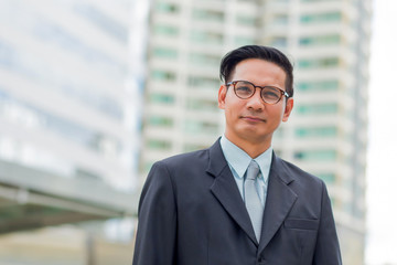 Fototapeta premium Asia young business man in front of the modern building in downtown .Concept of young business people