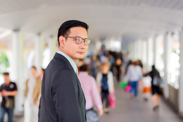 Young Asia handsome businessman with his glasses standing on walkway of modern city.