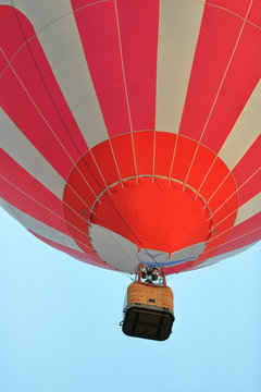 Kosz podpięty do kolorowego balonu, widok z dołu, w powietrzu, widoczna dolna część czaszy balonu