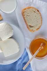 Cheese and honey on a white plate, kefir, a sandwich with soft cheese, minimalism, honey, a piece of bread, blue napkin, French breakfast on a white background, American cuisine