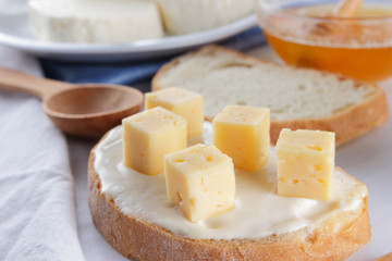 Cheese and honey on a white plate, kefir, a sandwich with soft cheese, minimalism, honey, a piece of bread, blue napkin, French breakfast on a white background, American cuisine