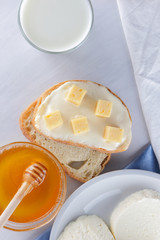Cheese and honey on a white plate, kefir, a sandwich with soft cheese, minimalism, honey, a piece of bread, blue napkin, French breakfast on a white background, American cuisine