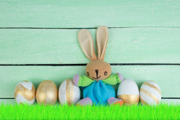 Happy Easter. Colorful easter eggs and rabbit on green grass.