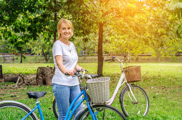 Elderly woman with a bicycle in the nature at the park.