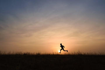 Kid running across the horizon at sunrise