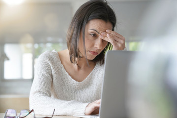 Woman working on laptop having a headache