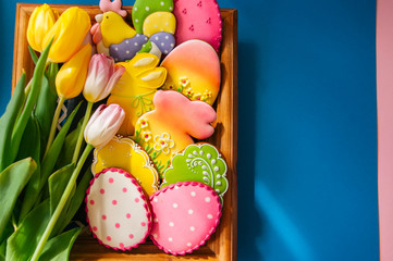 Fototapeta na wymiar Colorful Easter bunny and egg cookies in a basket on a wooden background