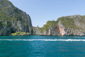 scenic view of rocky formations covered with green plants, blue sky and ocean, phi phi islands