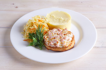Fish cutlet with ham and melted cheese topping served with pickled cabbage and mashed potato