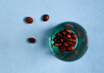 coffee beans in green glass Cup on blue background. minimalism