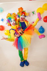 Obraz na płótnie Canvas Clowns are a boy and a girl in bright costumes at the child's birthday. The explosion of emotions and the fun of the circus