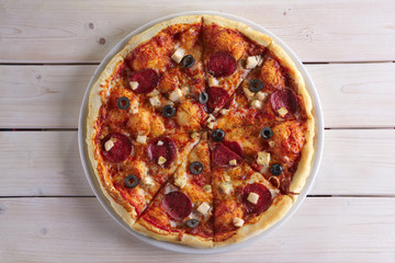 Pizza with sausage, ham, tomato, zucchini and paprika