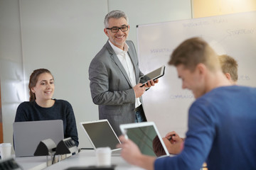 Teacher giving economics class, using whiteboard
