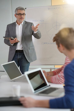 Teacher giving economics class, using whiteboard