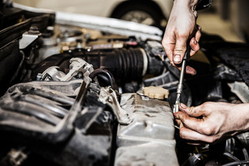 Automobile service worker or garage mechanic repairing auto car engine