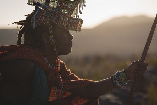 Maasai man in traditional clothing sitting at countryside