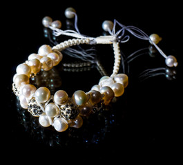 Handmade bracelet made of pearls on a glossy black background
