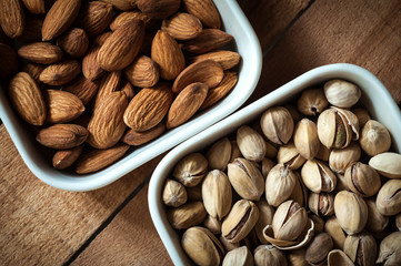Almond kernels and pistachio nuts lie on white saucers