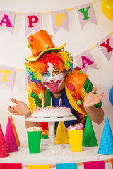 Clowns are a boy in bright costumes at the child's birthday. A table with refreshments and a cake. The explosion of emotions and the fun of the circus. greed and desire to eat cake