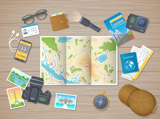 Preparing for hiking tour, vacation, travel. Planning, packing check list. Wooden table with tourist map, guidebook, tickets, passport, flashlight, action camera, compass, cap. Wooden table top view