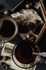 Two transparent cups of coffee, hazelnut, film camera and retro cards on a dark grunge background. The concept. Vintage. Flat lay. Toned