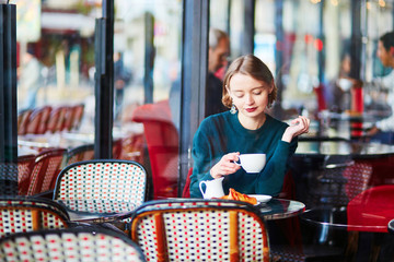 Young elegant woman drinking coffee in cafe in Paris, France - obrazy, fototapety, plakaty