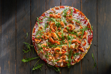 Tasty pizza with shrimp and arugula on a wooden table. Top view.
