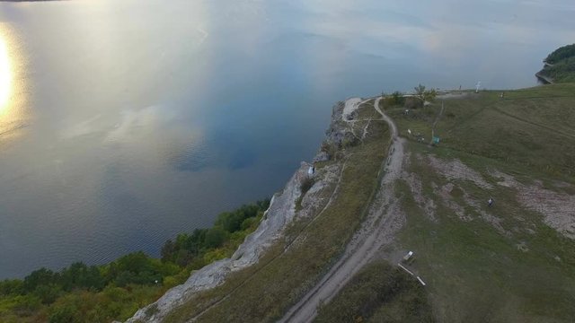 Great sunset on the lake between the mountains. A couple hugging at the edge of the cliff. 4k