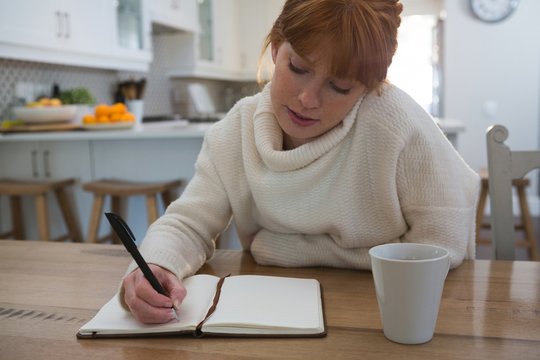 Woman writing on a diary at home
