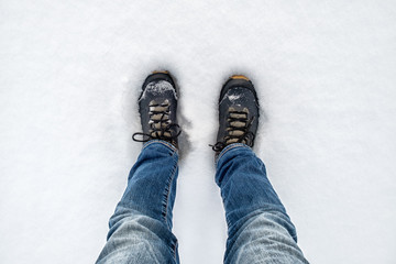 Feet in black trekking boots on snow